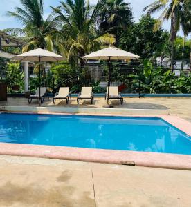 a swimming pool with two chairs and umbrellas at casa mexicana en sayulita in Sayulita