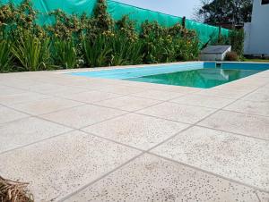 una piscina con suelo de baldosas y plantas en El nogalito quinta, en Lobos