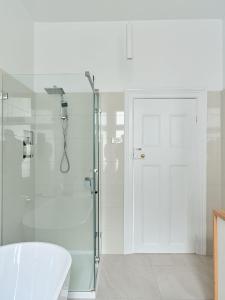 a white bathroom with a shower and a glass door at Sunny spacious three bedroom apartment with views in Hobart