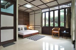 a bedroom with a bed and a chair and windows at Villa Marcolina 57 in Gadok 1 +55 photos