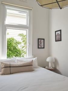 a bedroom with a white bed and a window at Sunny spacious three bedroom apartment with views in Hobart