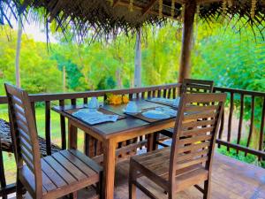 un tavolo e sedie in legno su una terrazza di legno di Rekawa Turtle Gate Hotel a Tangalle Altre 37 foto
