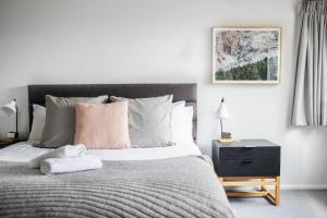 a bedroom with a bed and a nightstand with a pink pillow at Silvertop Chalet in Crackenback