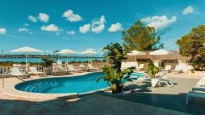 a swimming pool with lounge chairs and umbrellas at Apartamentos Paya II in Es Pujols