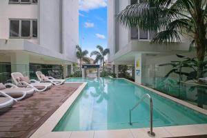 una piscina con sedie e un edificio di Starlit Palms - Chic Poolside Haven by the Beach a Gold Coast