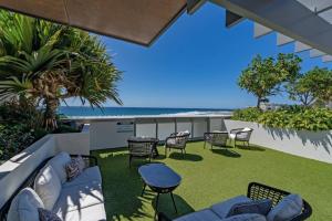 un patio con sedie, tavoli e spiaggia di Starlit Palms - Chic Poolside Haven by the Beach a Gold Coast