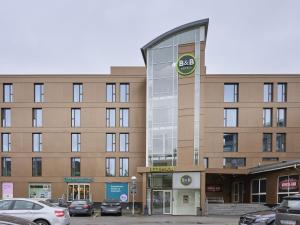 瓦埃勒B&B HOTEL Vejle的一座大楼，停车场里停满了汽车