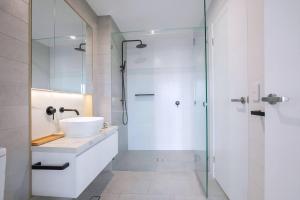 un bagno con lavandino e doccia in vetro di Starlit Palms - Chic Poolside Haven by the Beach a Gold Coast