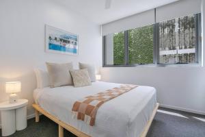 una camera bianca con un letto e due finestre di Starlit Palms - Chic Poolside Haven by the Beach a Gold Coast