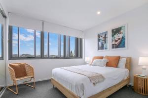 una camera da letto con un letto, una sedia e finestre di Starlit Palms - Chic Poolside Haven by the Beach a Gold Coast