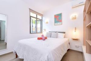 Green Nest Peyrebère في بيريبير: غرفة نوم مع سرير أبيض مع حيوان محشو وردي عليه