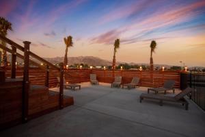 a deck with benches and palm trees at sunset at Ranch House with Lap Pool Biking & Running Course in Desert Hot Springs