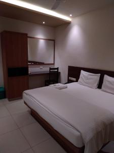 a bedroom with a large bed and a flat screen tv at Sri bhavan residency in Palakkad +2 photos
