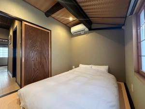 1 dormitorio con 1 cama blanca grande y puerta de madera en Shirakabanoyado - UCHIKYUHOJI, 白樺の宿 - 堂庭, en Osaka 12 fotos más