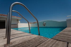 um passeio marítimo que leva a uma piscina com água azul em Hotel Grand Cap Rooftop Pool em Agde