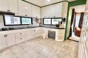 una cucina con armadi bianchi e parete verde di h6市中心 唐人街 航站楼 风月街五房芭提雅海天-泳池别墅o a Centro di Pattaya