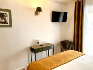 a hotel room with a bed and a tv on the wall at Hotel Lou Marquès in Saintes-Maries-de-la-Mer