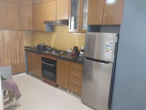 a kitchen with a stainless steel refrigerator and wooden cabinets at Coquilles D'Argent Apart in Flic-en-Flac