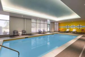 a pool in a hotel room with chairs and tables at Tru By Hilton Charlotte Tyvola I-77 in Charlotte