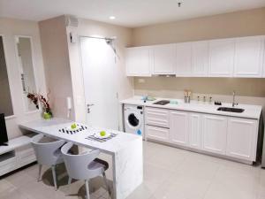 a kitchen with white cabinets and a table and chairs at Paris Cozy House in Shah Alam