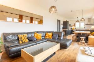 a living room with a black leather couch at Maison Valérie à 1km plage in Trégunc +21 photos