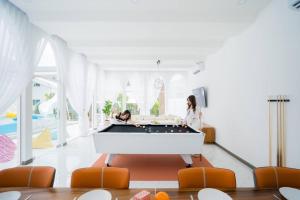 two women playing pool in a living room with a pool table at Sugar beach pool villa Cha-am บ้านพักชะอำ พูลวิลล่าชะอำ ใกล้ทะเล in Cha Am