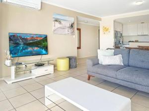 un soggiorno con un divano blu e una TV di Unit 24 - Avoca Palms Resort ad Avoca Beach