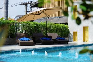 a group of chairs and an umbrella next to a pool at Hotel M Chiang Mai in Chiang Mai