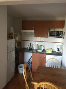 a kitchen with a table and chairs and a refrigerator at Appartement bonascre in Ax-les-Thermes