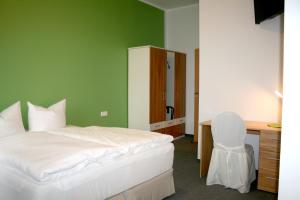 a bedroom with a bed and a desk and a chair at Lindencafe Luckenwalde in Luckenwalde