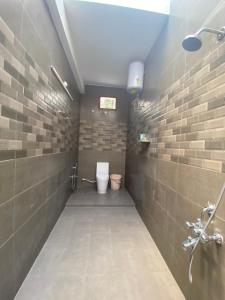 a bathroom with a toilet in a brick wall at Wooden cottage in Kanchipuram