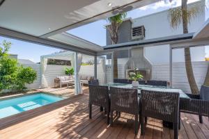 a patio with a table and chairs and a swimming pool at Beachside Retreat with Private Pool in Papamoa