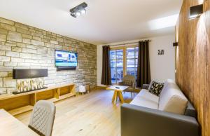 salon z kanapą i kamienną ścianą w obiekcie Bolodges Apartments by Alpin Rentals w Saalbach Hinterglemm