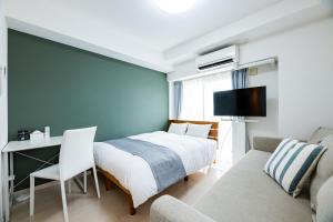a bedroom with a bed and a desk and a couch at Presence Hakata in Fukuoka