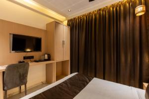 a hotel room with a bed and a desk and a television at Hotel Windsor Castle in Mumbai