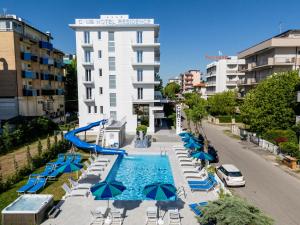 una piscina con sedie e ombrelloni di fronte a un edificio di ClubHotel Residence Cesenatico a Cesenatico