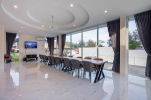 Un comedor con una mesa larga y sillas. en Royal beach pool villa cha-am บ้านพักชะอำ พูลวิลล่าชะอำ ใกล้ทะเล, en Cha Am