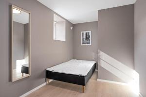 a small bedroom with a bed and a mirror at 6 sov l Perfekt for StayCATION in Drammen
