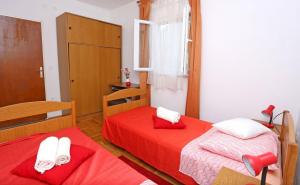 2 Betten in einem Zimmer mit roter Bettwäsche und weißen Handtüchern in der Unterkunft Apartment Marija in Drvenik Mali