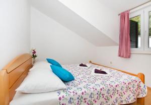 a bedroom with a bed with blue pillows and a window at House Miho in Omiš