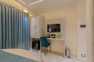 a room with a bed and a chair and a television at Hotel Windsor Castle in Mumbai