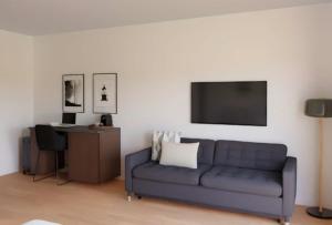 a living room with a blue couch and a tv at Madrid Suites Moncloa-Aravaca, SOLO CHECK IN ON LINE - PARKING GRATUITO in Madrid +6 photos