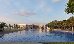 una grande piscina di fronte a un edificio con palme di THH OCEANAMI Resort & Villa Vung Tau a Long Hai
