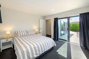 Un dormitorio con una cama y una puerta corrediza de vidrio. en Private Escape, en Martinborough