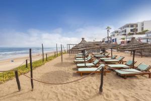 a row of chairs and umbrellas on a beach at Apprt cosy près plage des Nations in Salé