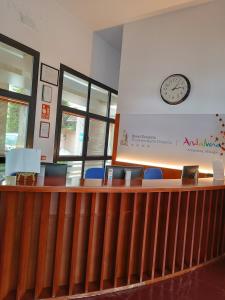 a waiting room with a clock on the wall and chairs at Hotel Escuela Convento Sto Domingo in Archidona