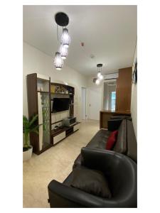 棉兰Podomoro Exclusive Pool View Apartment-5th Floor-Min 2N的客厅里有一张黑色沙发和一台电视