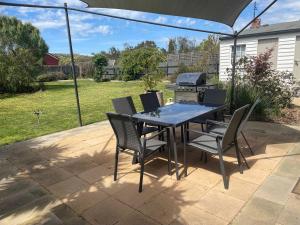 a patio with a table and chairs and a grill at The Baker's Cottage in the Heart of Richmond Sleeps 6 in Hobart