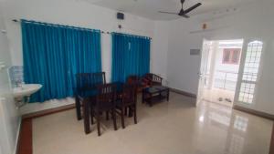 a dining room with blue curtains and a table and chairs at Azza Home in Cochin
