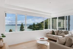 Una sala de estar con un sofá y una ventana grande. en Panorama Penthouse Luxe Ocean Views & Pool, en Mount Maunganui